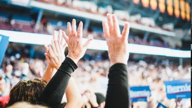 Audience members with their hands up at an American political rally