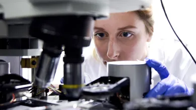 Doctor Katrina Morgan conducting research into novel glass beneath a microscope.