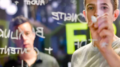 A man writing ideas on a glass wall with a marker pen