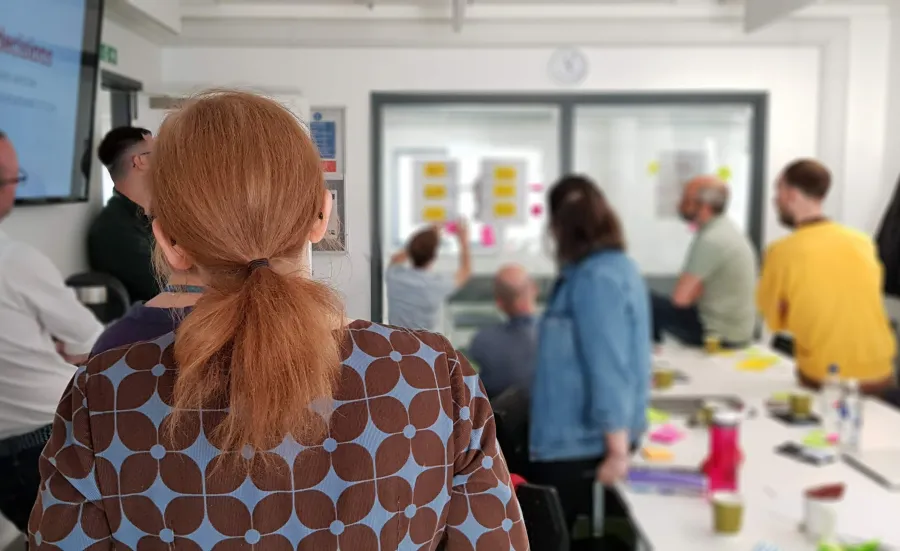 A team workshop with people gathering around a large screen