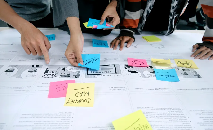 Several pairs of hands posting sticky notes on hand drawn designs