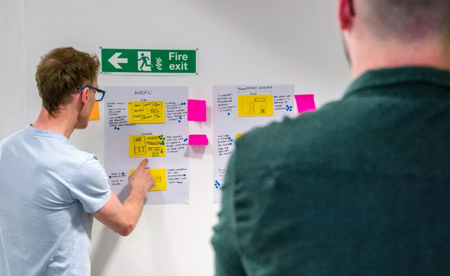 Two male team members participating in a workshop with sticky notes