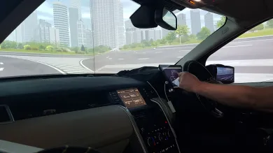 A student's arm on the steering wheel of a driving simulator