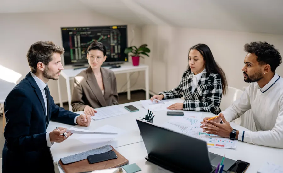 Group of 4 people talking around a work table