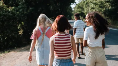 Teenagers walking down a sunny country lane away from the camera