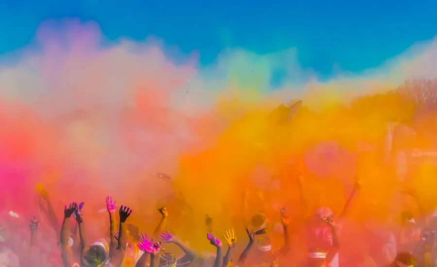 Group of people throwing coloured powder in the air