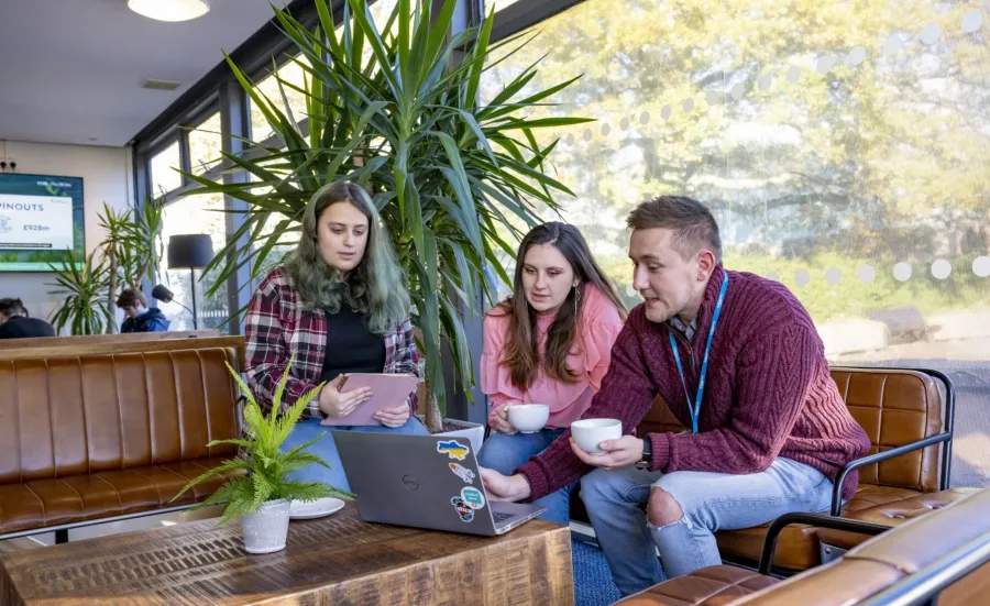 3 students from the Accessibility Allies team sitting in the café at Highfield Campus, gathered around a laptop in discussion.