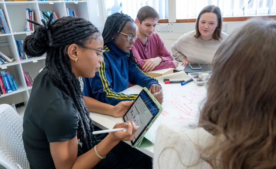 Ria Moses in a group meeting holding an iPad