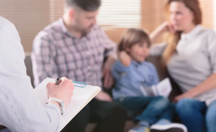 A therapist take notes while interviewing a family