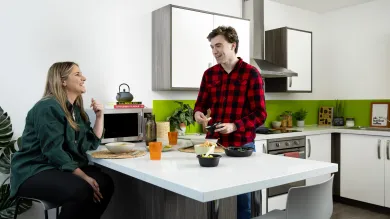 2 students talking while preparing food in a kitchen