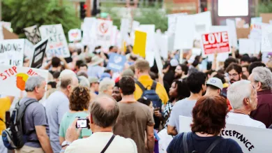 Pexels image of people taking part in a rally, with placards, rucksacks and phones