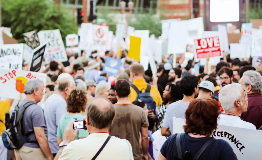 Pexels image of people taking part in a rally, with placards, rucksacks and phones