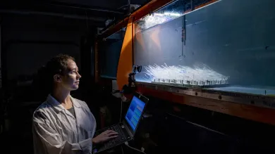 A researcher with a laptop measuring underwater flow in a water tank