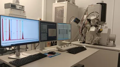 Focus Ion Beam (FIB) Facility. The image shows three screens with data displayed. There is lab equipment in the background.