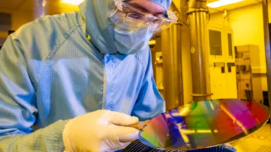 A researcher in a cleanroom suit with a 200mm wafer in the nanofabrication cleanroom