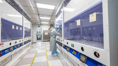 A researcher in a cleanroom suit using the acid wet benches in the nanofabrication cleanroom