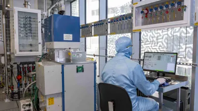 A researcher in a cleanroom suit uses an Inductively Coupled Plasma Etcher