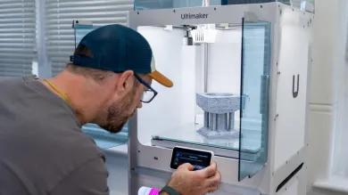 A technician adjusts the settings on the control panel of a 3D printer