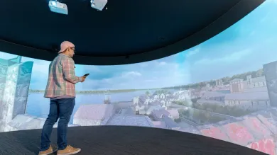 A person stands in our Igloo Immersive Environment facility, interacting with immersive content via a handheld device