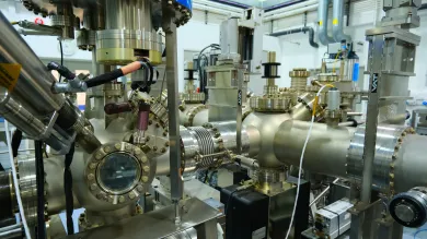 complex assembly of industrial machinery, likely a component of a laboratory or manufacturing facility. The machinery is composed of shiny metal parts, including cylindrical and conical segments connected with various flanges and bolts.