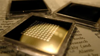 three small square microchips placed on the pages of a book with visible text.