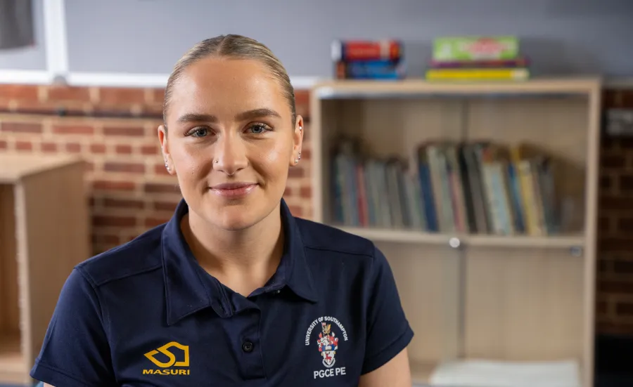 Head and shoulders portrait image of Alice wood wearing a navy blue tee shirt with a University PGCE PE logo.