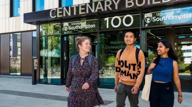Three students walking outside the entrance to Centenary Building, also known as Building 100, on the University of Southampton's Highfield campus.