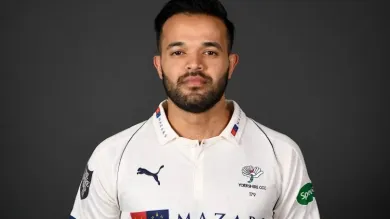 Azeem Rafiq in Yorkshire cricket shirt, facing camera against a dark background.