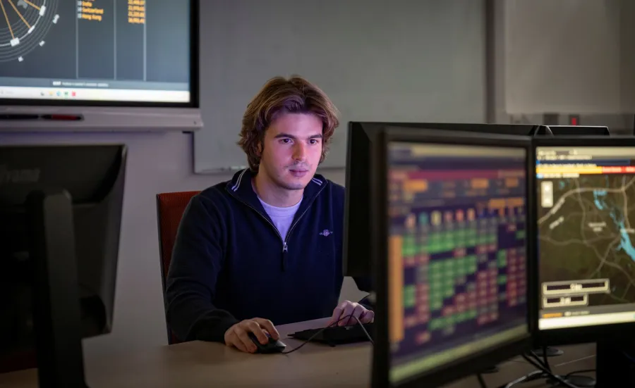 Stefan using a computer in a classroom for his finance and economics degree. 