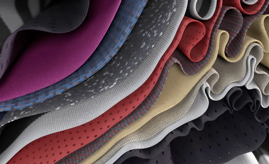 A close-up view of layered, folded fabrics in different colours and textures, shown in a wavy, rippled arrangement.