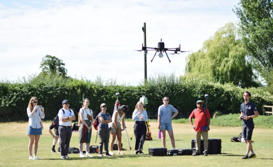 A group of people out on a field using an aerial drone.