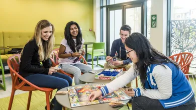Students sitting around a table playing games in the common room.