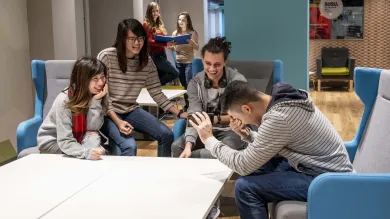 Students sitting and talking around a table in the common room.