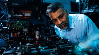 Researcher adjusting advanced laser and optical equipment during an experiment in a scientific laboratory.