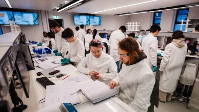 A group praclical taking place in the Biomedical engineering laboratory. Students are wearing white coats and eye protection.