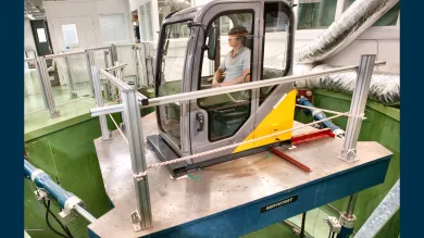 Person operating an excavator cab simulator on a motion platform in the Vibration and Simulation Laboratory