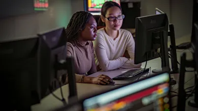 two students seated in front of a computer monitor
