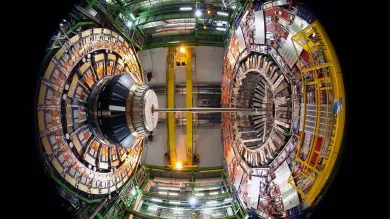 A fisheye-style image of the large particle detector at CERN, with concentric layers of detection equipment and metal support structures.