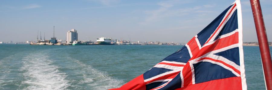 view from a boat looking back at the red ensign flag and port