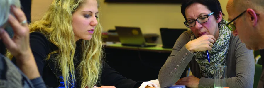 4 people around a table looking at a document