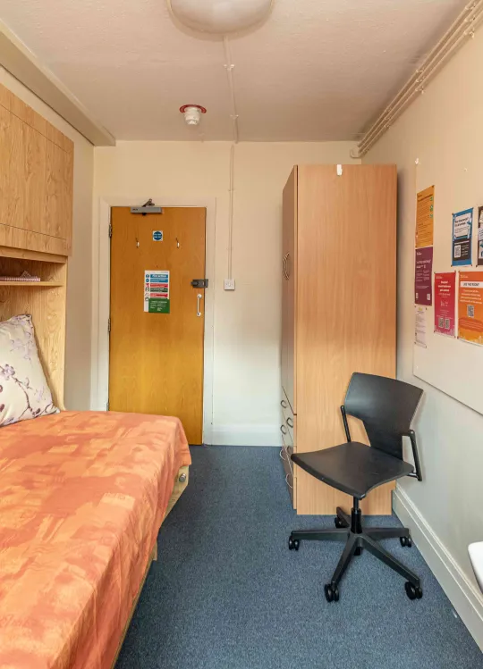 Highfield hall studybed room including bed, wash basin, chair, shelves and cupboards.