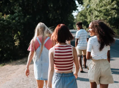 Teenagers walking down a sunny country lane away from the camera