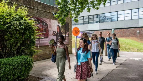 A student leads a group of visitors on a tour of campus.