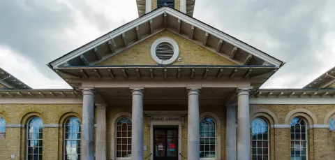 Exterior view of impressive stone building with columns and canopy.