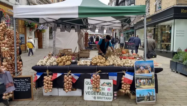 A market stall adorned with French flags, selling fresh fruit and vegetables.