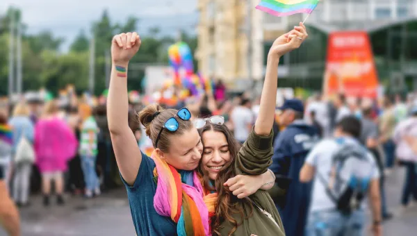 2 ladies hugging at a gay pride parade.