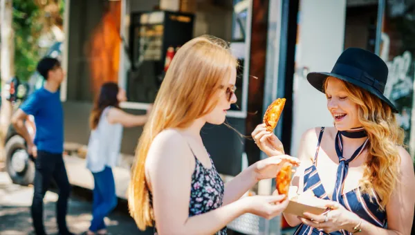 Students eating at a food festival on a sunny day.