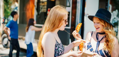 Students eating at a food festival on a sunny day.