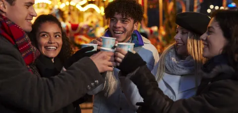 Group of friends saying cheers at a christmas market. 