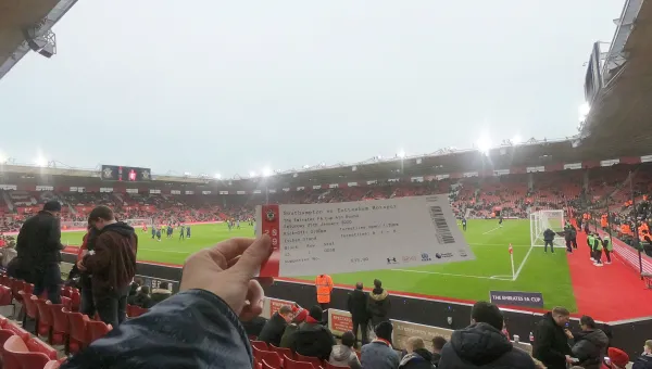 Student holding match ticket in the stands of St Mary's Stadium during a match.